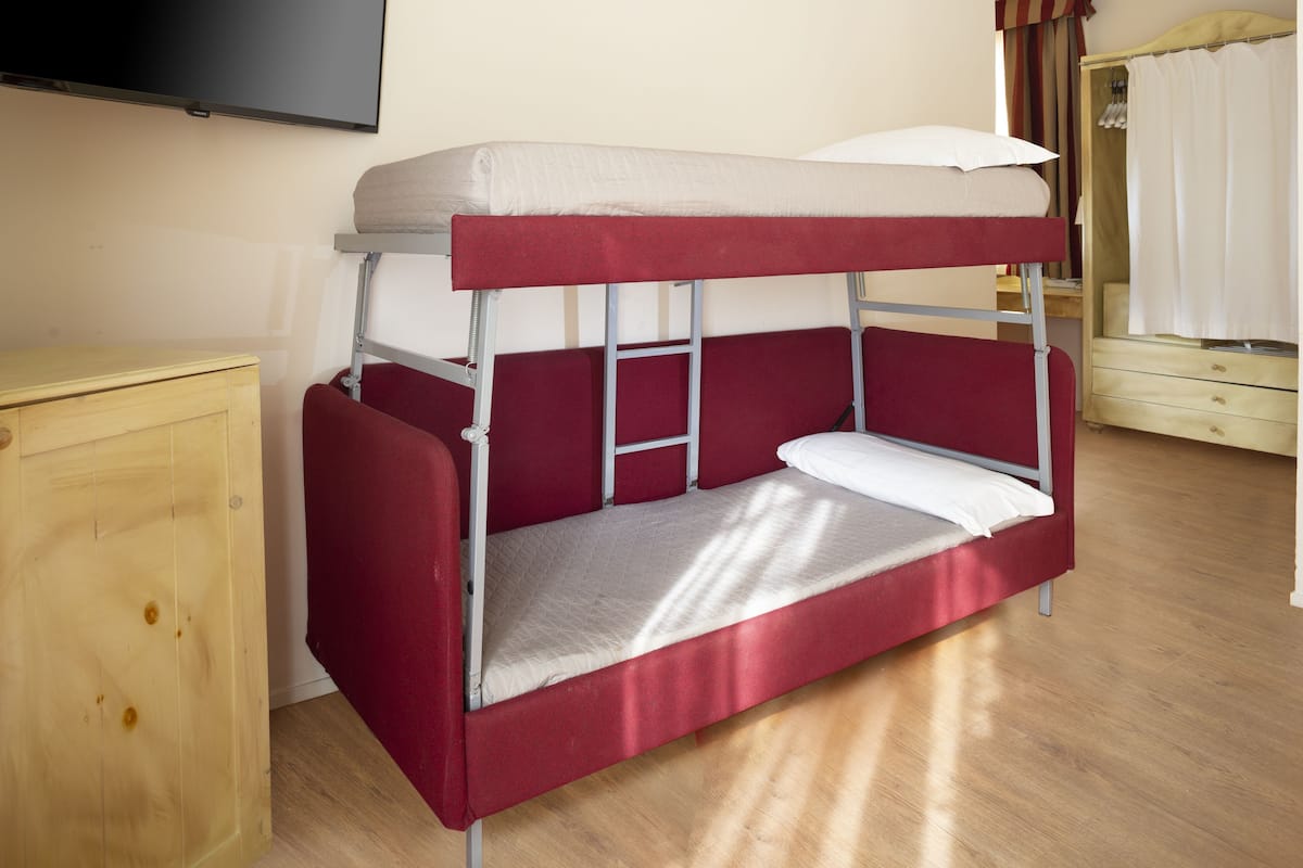 A bunk bed with a wooden cabinet and a mirror.