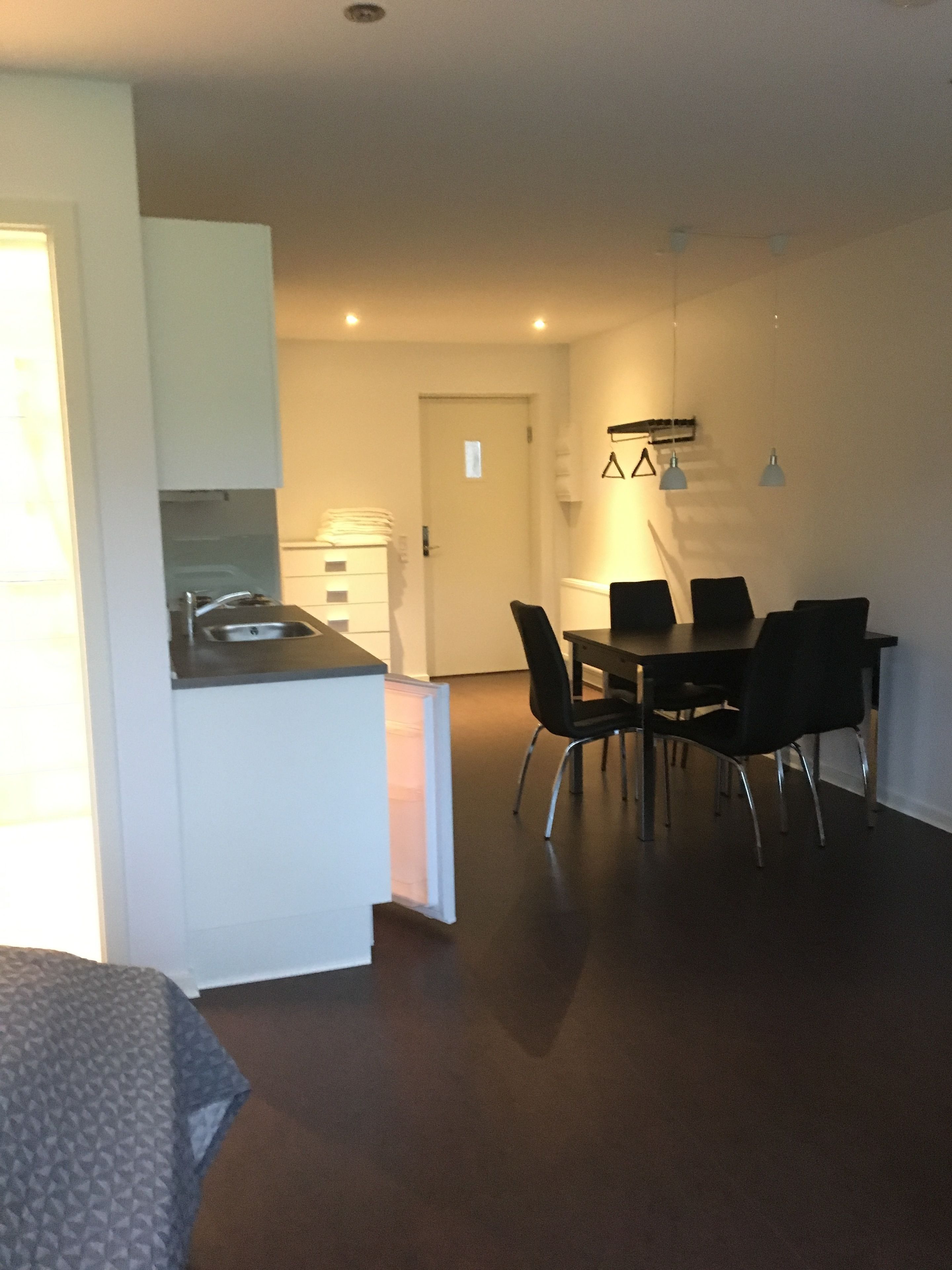 A compact living space with a kitchenette, dining area, and a door leading to another room.