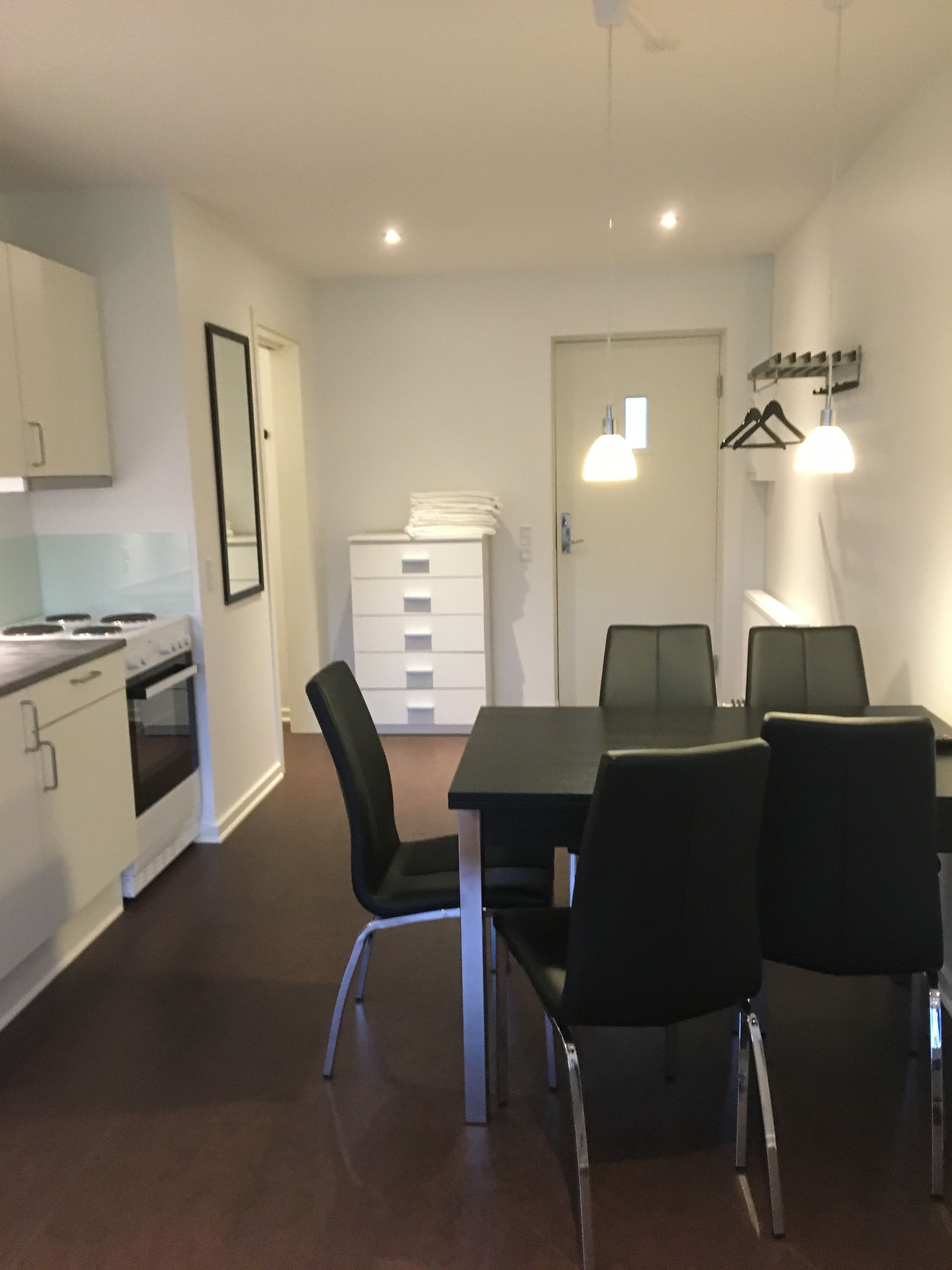 A modern kitchen with white cabinets, a stove, and a dining area with a table and chairs.