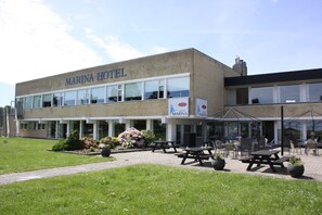 A Marina Hotel with a patio area featuring outdoor seating and potted plants. - Hotel Marina (Grenaa)