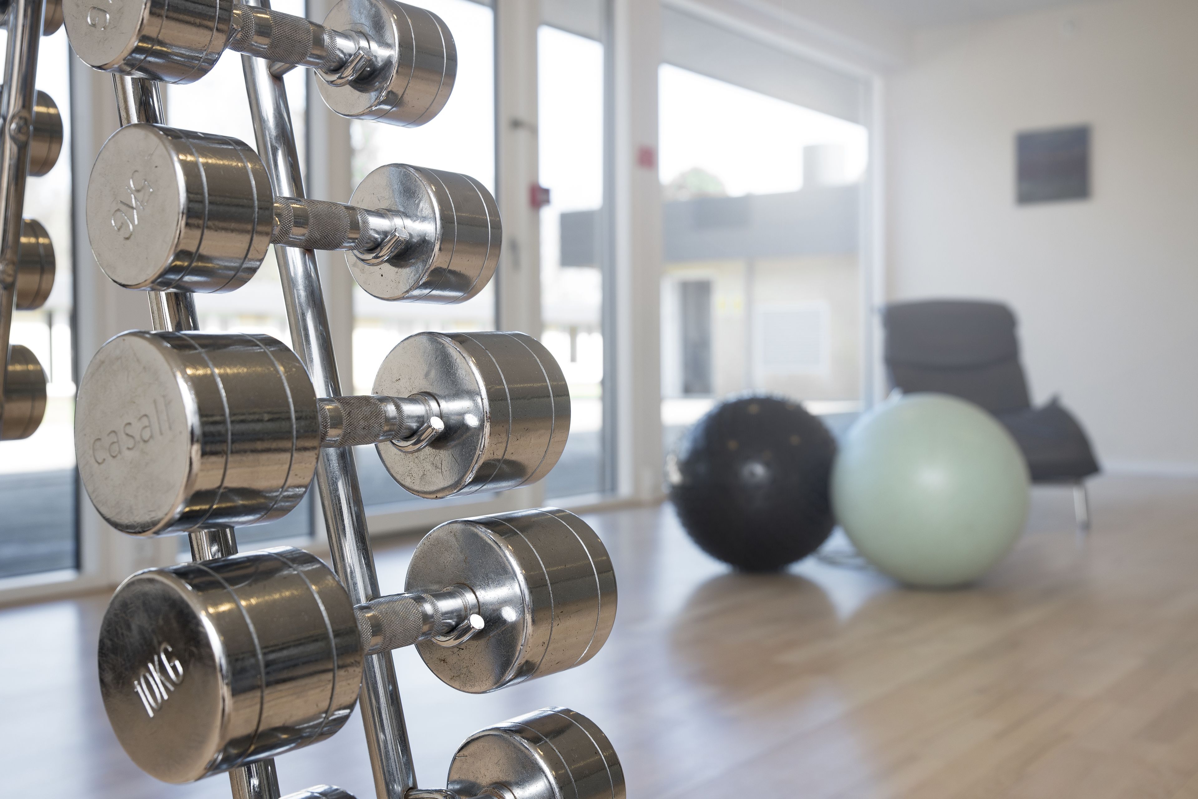 A gym with a weight rack and exercise balls.