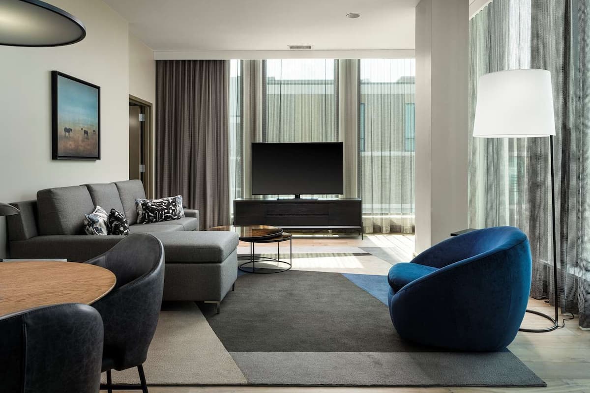 A modern living room with a grey sofa, a blue armchair, a coffee table, and a flat-screen TV.