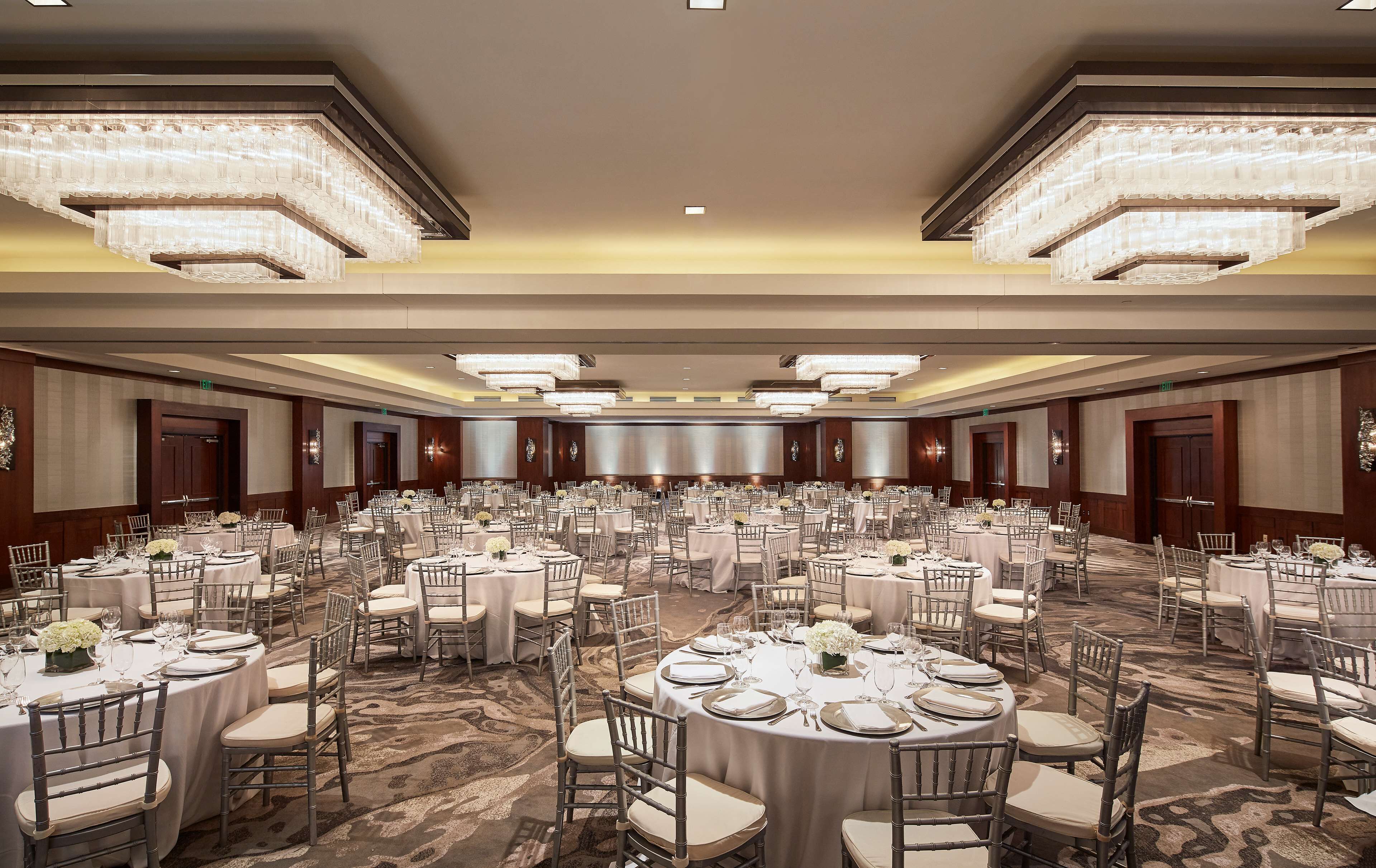 Un amplio salón de banquetes con mesas redondas, sillas y candelabros.