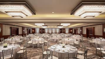 Un amplio salón de banquetes con mesas redondas, sillas y candelabros.