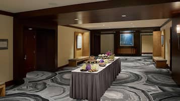Un vestíbulo de hotel con una larga mesa de recepción, bancos y una alfombra estampada.
