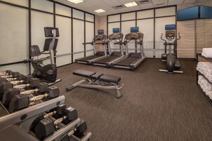 Un gimnasio con cintas de correr, máquinas de pesas y mancuernas.