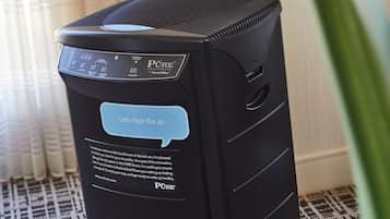 Un purificador de aire negro con pantalla digital y el mensaje 'Aclaremos el ambiente'.