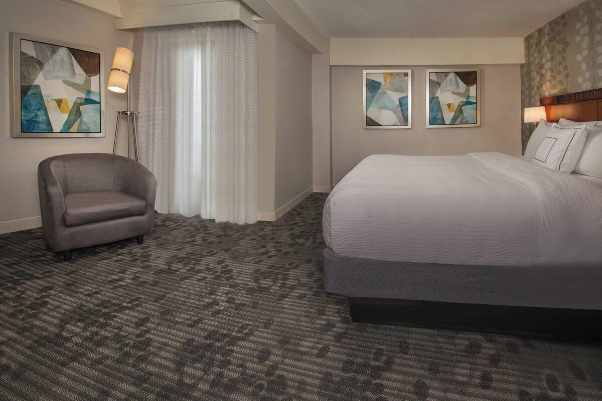 Una habitación de hotel con una cama grande, una silla y arte abstracto en las paredes.