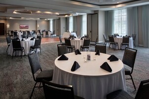 Un salón de conferencias con varias mesas redondas, cada una dispuesta con sillas y centros de mesa.