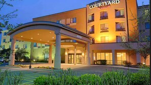 Un hotel Courtyard Marriott con entrada cubierta, varios pisos y fachada bien iluminada.