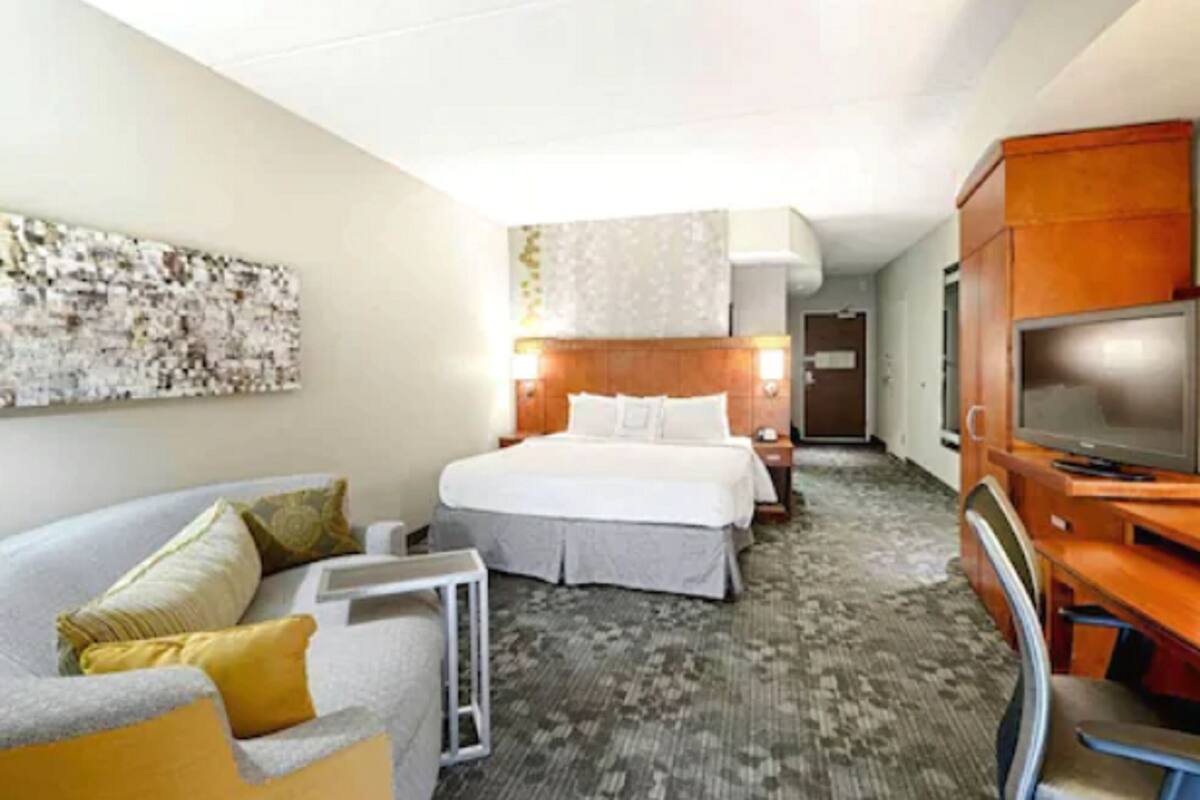 A hotel room with a bed, a TV, a desk, and a sofa.