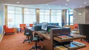 Un espacio de oficina moderno con múltiples estaciones de trabajo, sillas ergonómicas y una zona de estar cómoda con sofá y sillones.