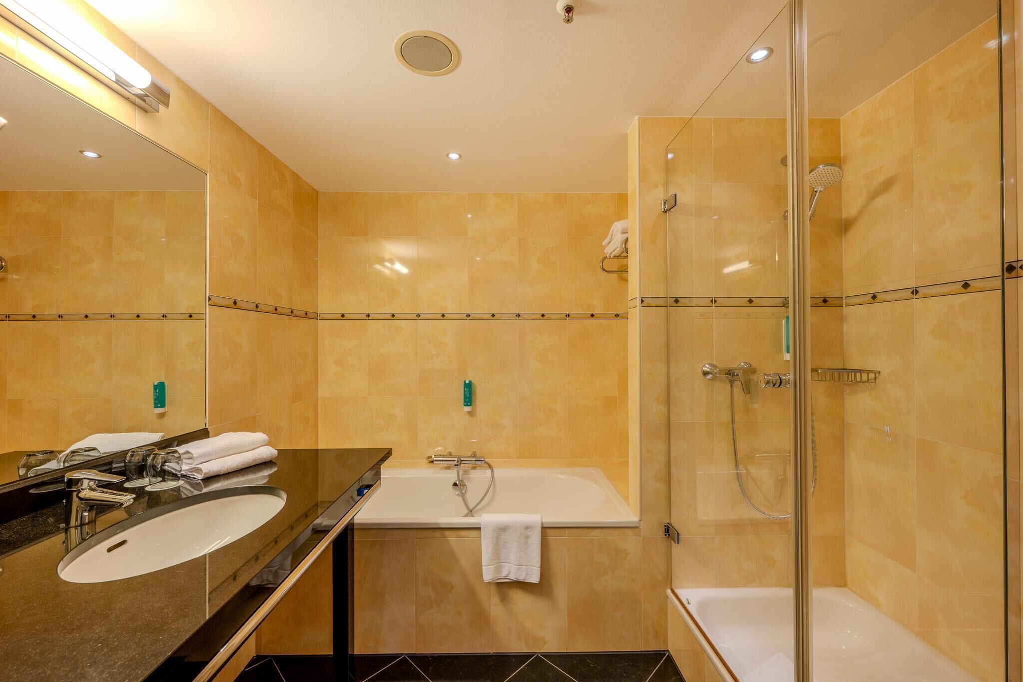 Ein modernes Badezimmer mit einem großen Spiegel, einer Badewanne und einer Duschkabine.