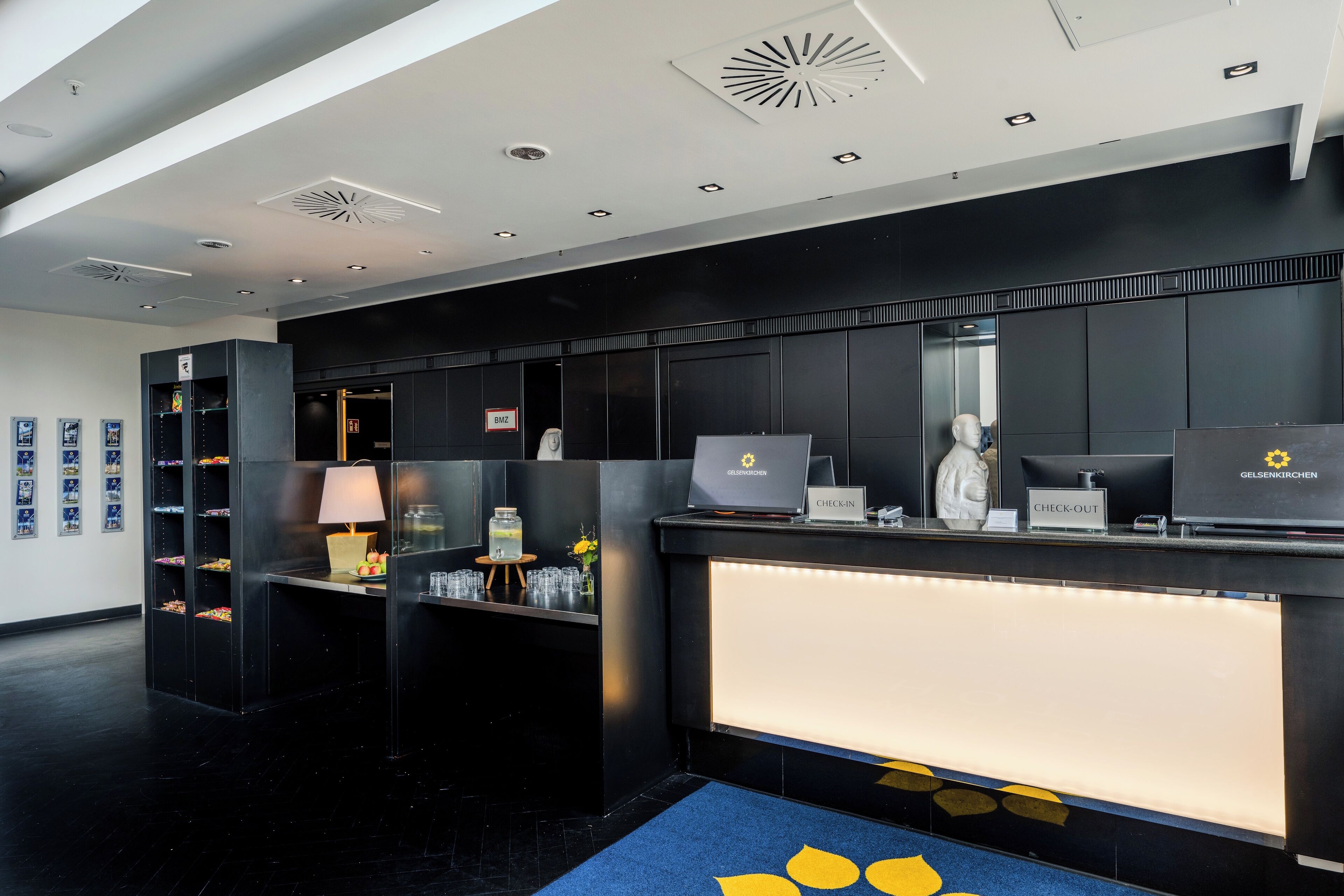 Ein Hotel-Rezeptionsbereich im modernen Design mit einer Rezeption, einem Computer und einem Check-in-Schalter.