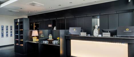A hotel reception area with a modern design, featuring a reception desk, a computer, and a check-in counter.
