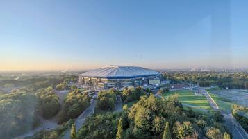 Ein Stadion, umgeben von Grünflächen und unter blauem Himmel.