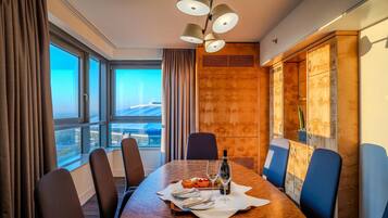 A conference room with a large table, chairs, a bottle of wine, and a fruit plate.