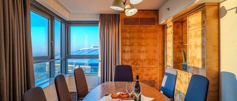 A conference room with a large table, chairs, a bottle of wine, and a fruit plate.