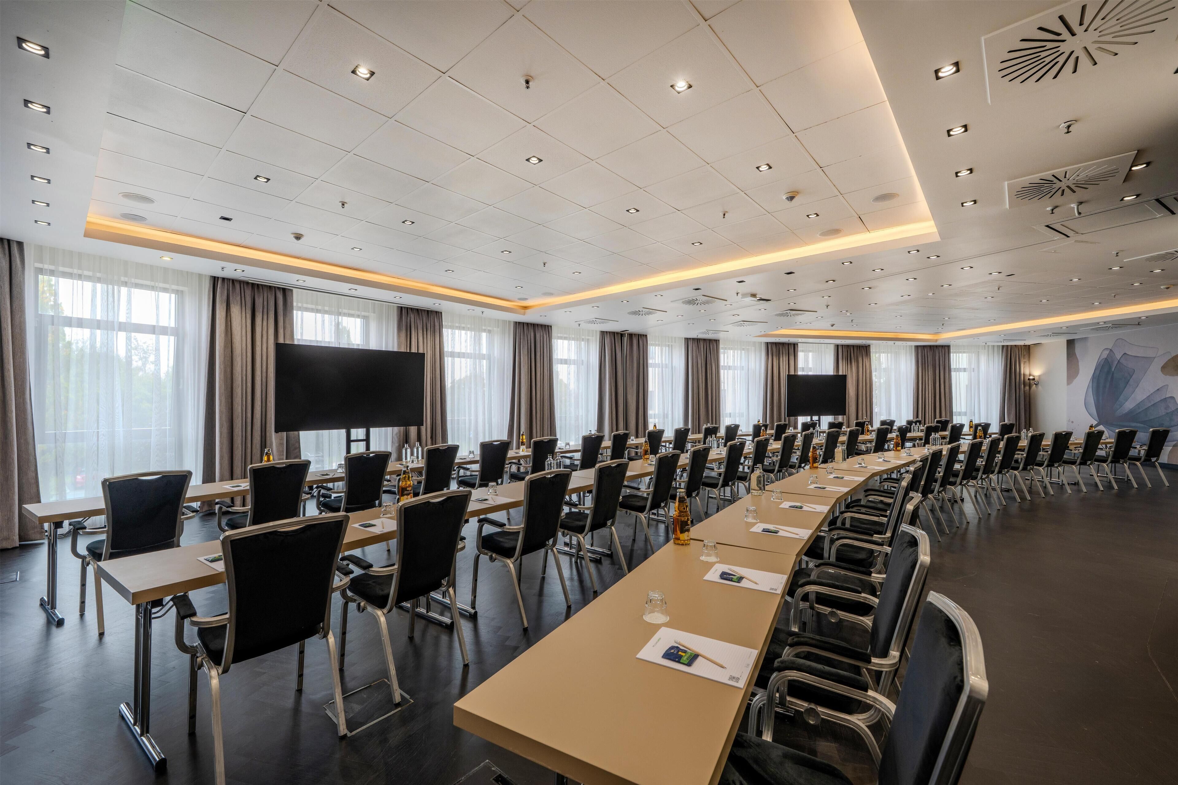 Une salle de conférence équipée d’une longue table, de chaises et d’un grand écran.