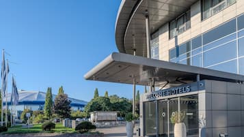 Ein moderner Hotelaufgang mit gewölbter Dachkonstruktion und großen Fenstern.
