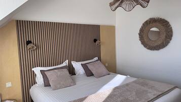A neatly made bed with a striped headboard, a woven wall hanging, and a small table with a lamp.