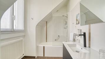 Un baño moderno con bañera, un espejo grande y una ventana.