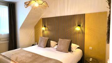 A bedroom with a sloped ceiling, a bed with pillows, a bedside table, and a wall-mounted lamp.