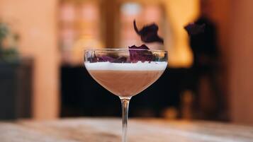 Un verre à cocktail orné de pétales de rose, posé sur une surface en bois.
