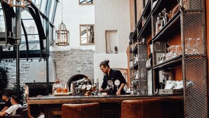 Zona de bar con taburetes, un barman y una grifo de cerveza.