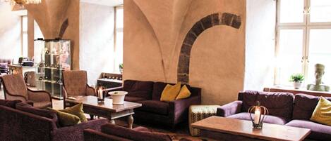A spacious lounge area with high arched ceilings, comfortable seating, and a chandelier.