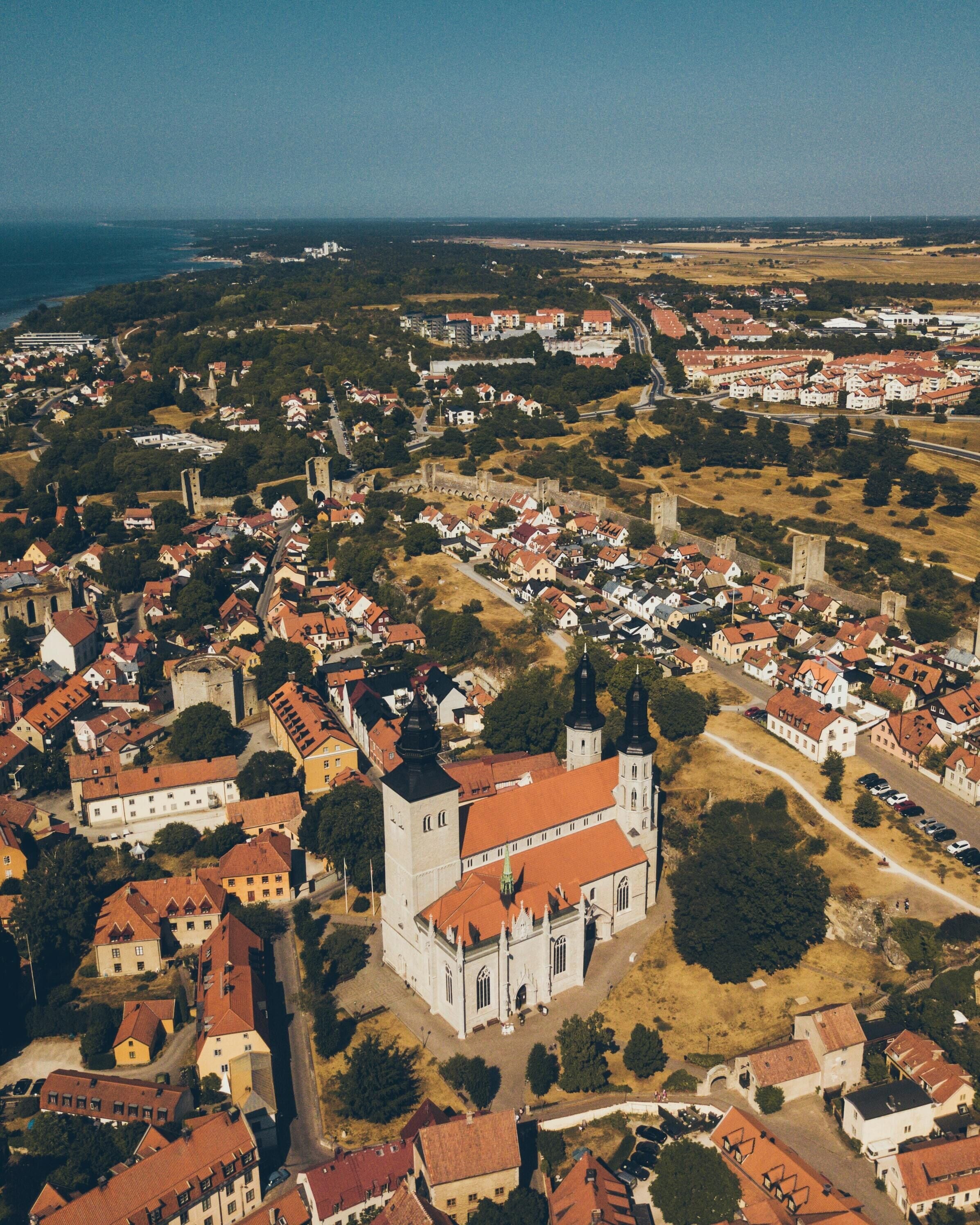 An aerial view of a town with a prominent church featuring a large tower and a fortified wall.