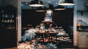 A kitchen with a central island, various kitchen utensils, and hanging lights.