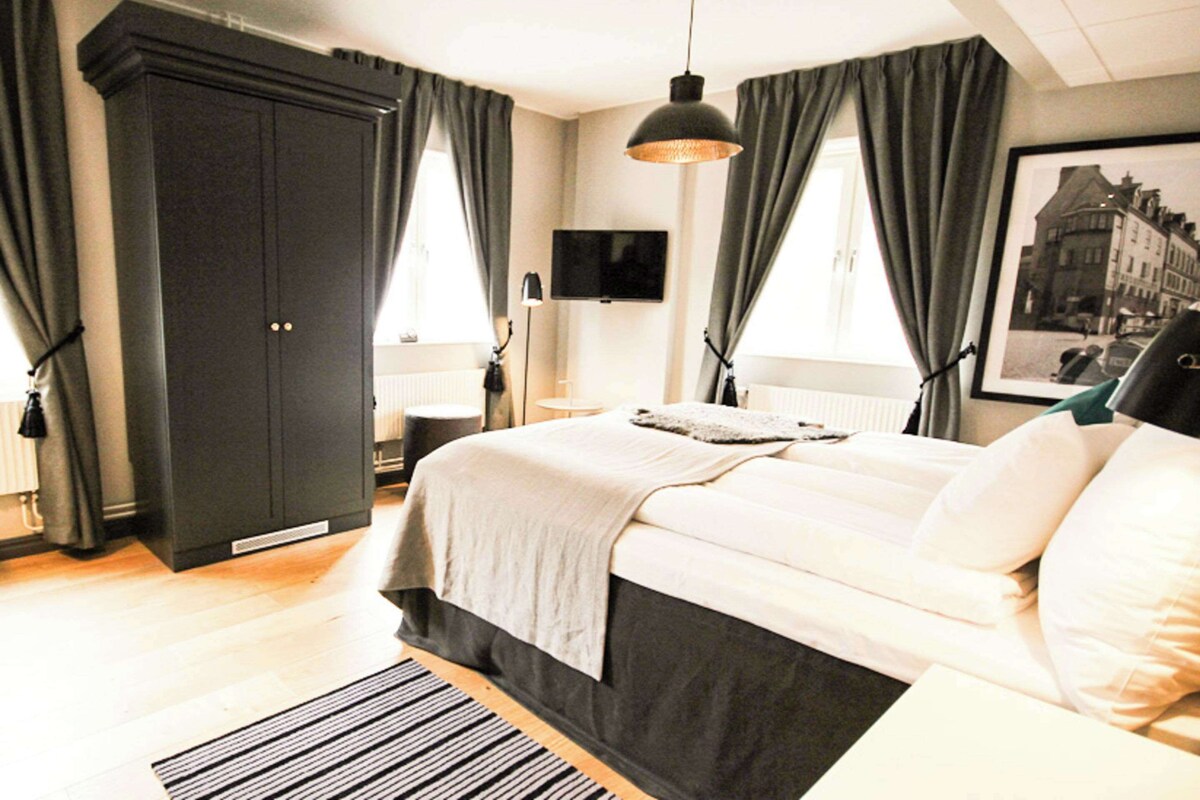 Un dormitorio con cama, armario, televisor y un cuadro en la pared.