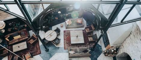 A spacious atrium with a high ceiling and large windows, featuring a variety of seating arrangements and decorative rugs.
