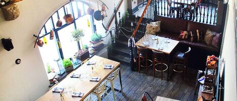 A dining area with multiple tables and chairs, a staircase, and a view of the outdoors.