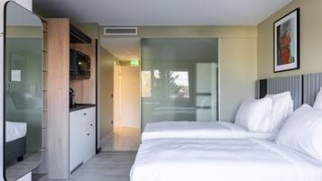 Et moderne hotelværelse med en stor seng, indbygget garderobe, et spejl og udsigt til det fri.
