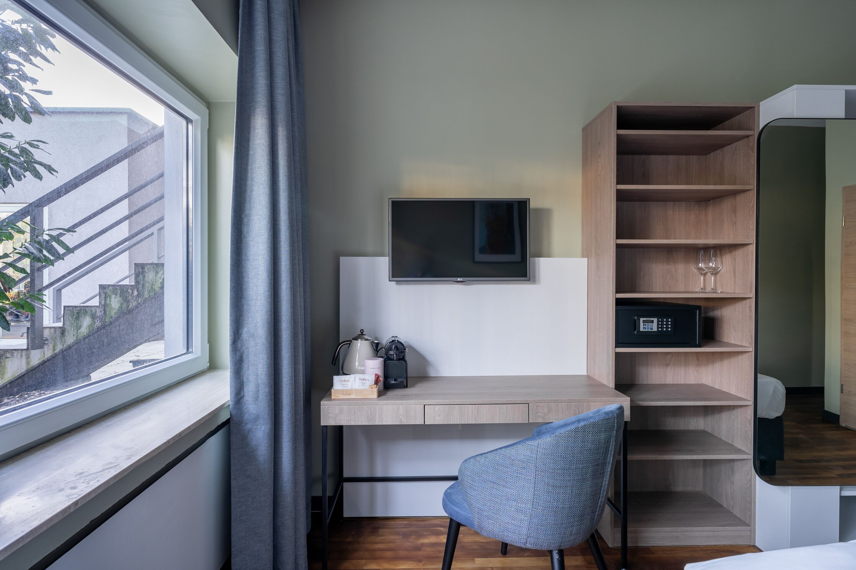 Moderni huone, jossa on työpöytä, tuoli, televisio ja sisäänrakennetut hyllyt.