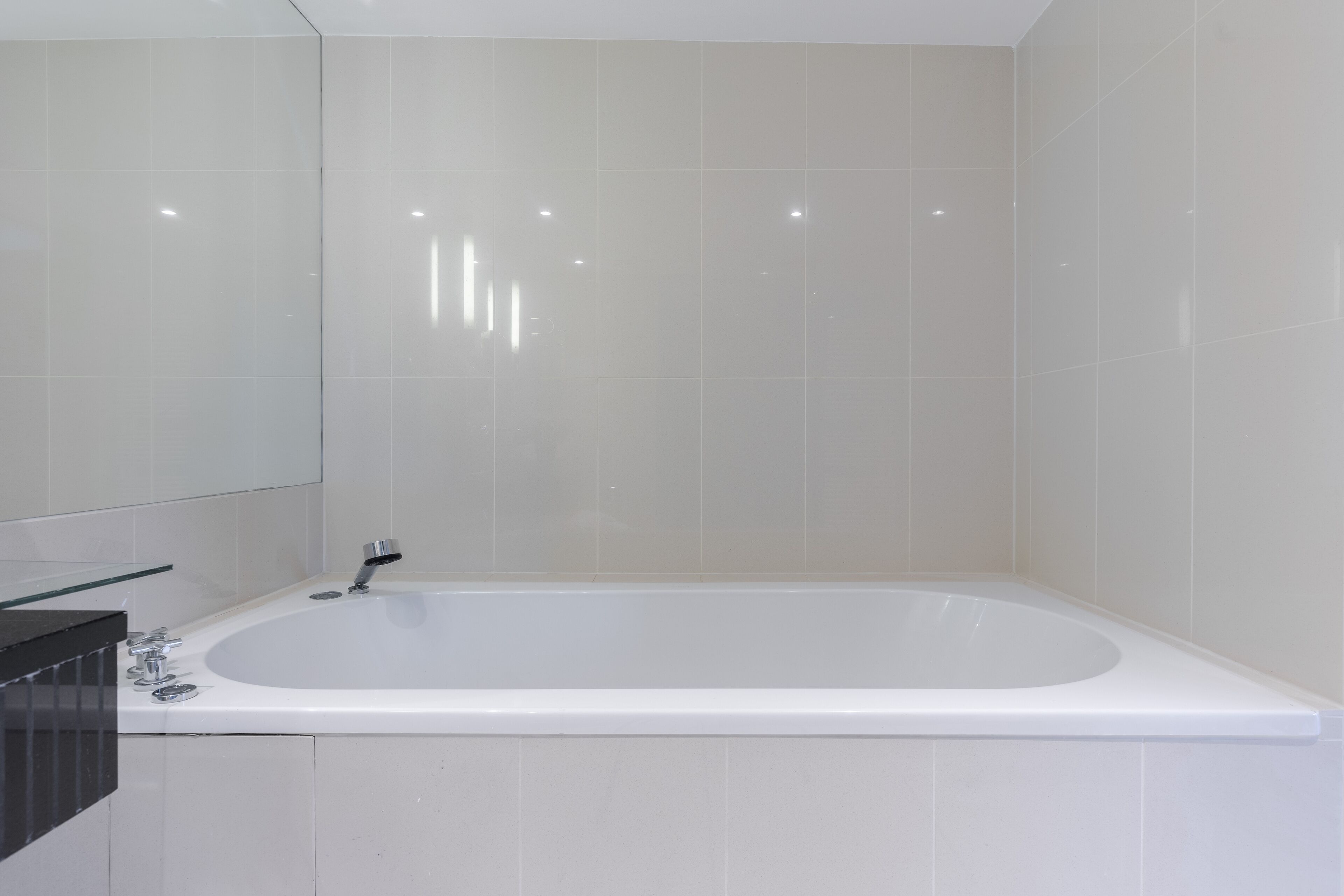 Une salle de bain moderne avec une grande baignoire, un miroir et un plan de toilette noir.