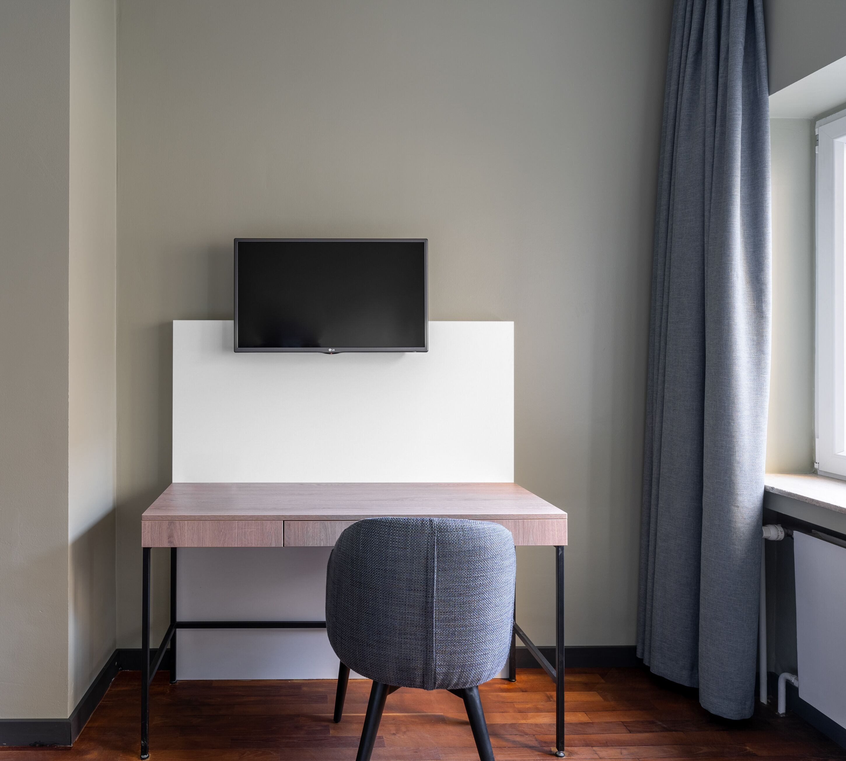 Ein modernes Zimmer mit einem Holztisch, einem grauen Stuhl und einem flachbildfernseher an der Wand.