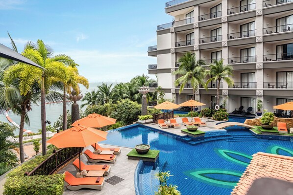Relax by the oceanfront pool surrounded by lounge chairs and umbrellas, with a unique wave-patterned floor.