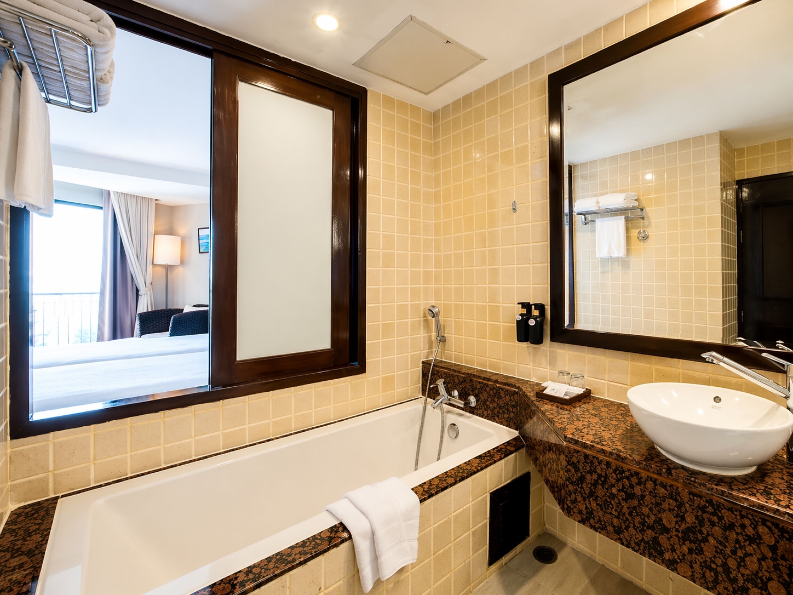 A hotel bathroom with a bathtub, sink, and large mirror.