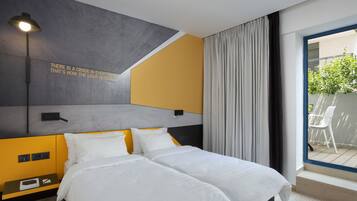 Habitación de hotel moderna con una cama, una mesita de noche, una lámpara y vistas al exterior.