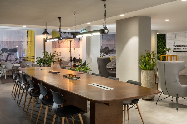 A modern conference room with a long wooden table, black chairs, and pendant lighting.