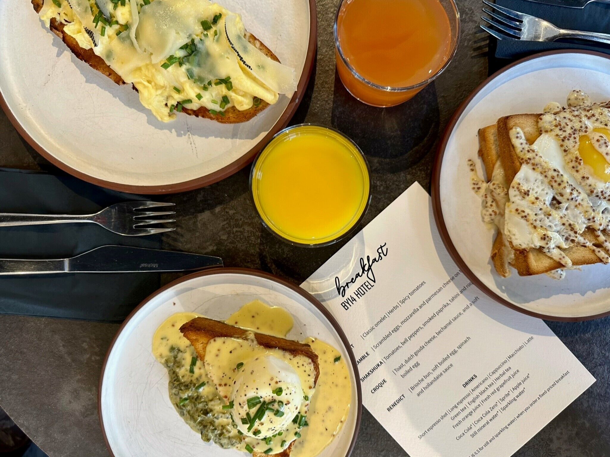 Una colazione con diversi piatti, tra cui Eggs Benedict e pane tostato, insieme a un menu che elenca le opzioni per la colazione.