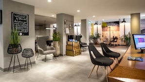Un vestíbulo moderno de hotel con mostrador de recepción, zona de estar y una pizarra con un mensaje de bienvenida.
