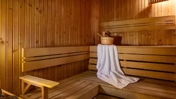 A wooden sauna with benches and a bench seat, a wooden bucket, and a towel.