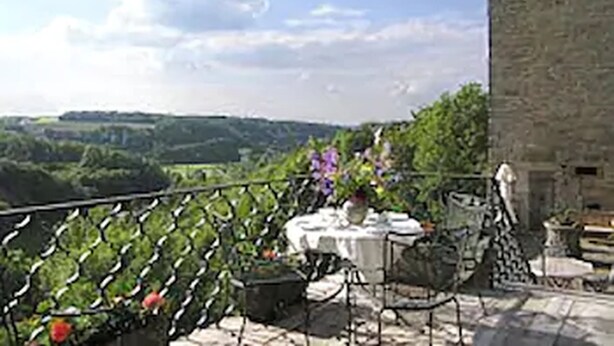 Un bâtiment en pierre doté d’un balcon donnant sur un paysage pittoresque.