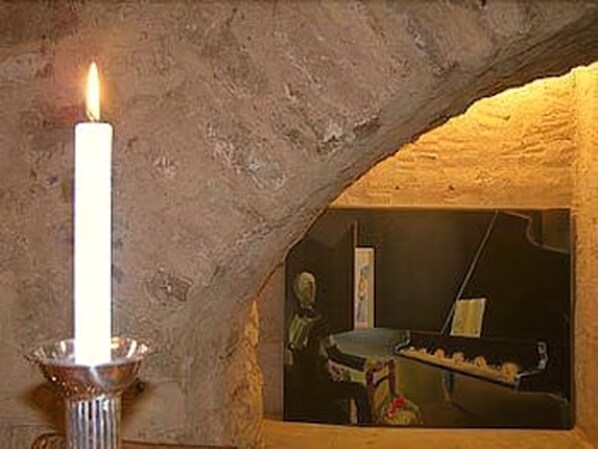 Una vela en un soporte de metal sobre una pared con textura.