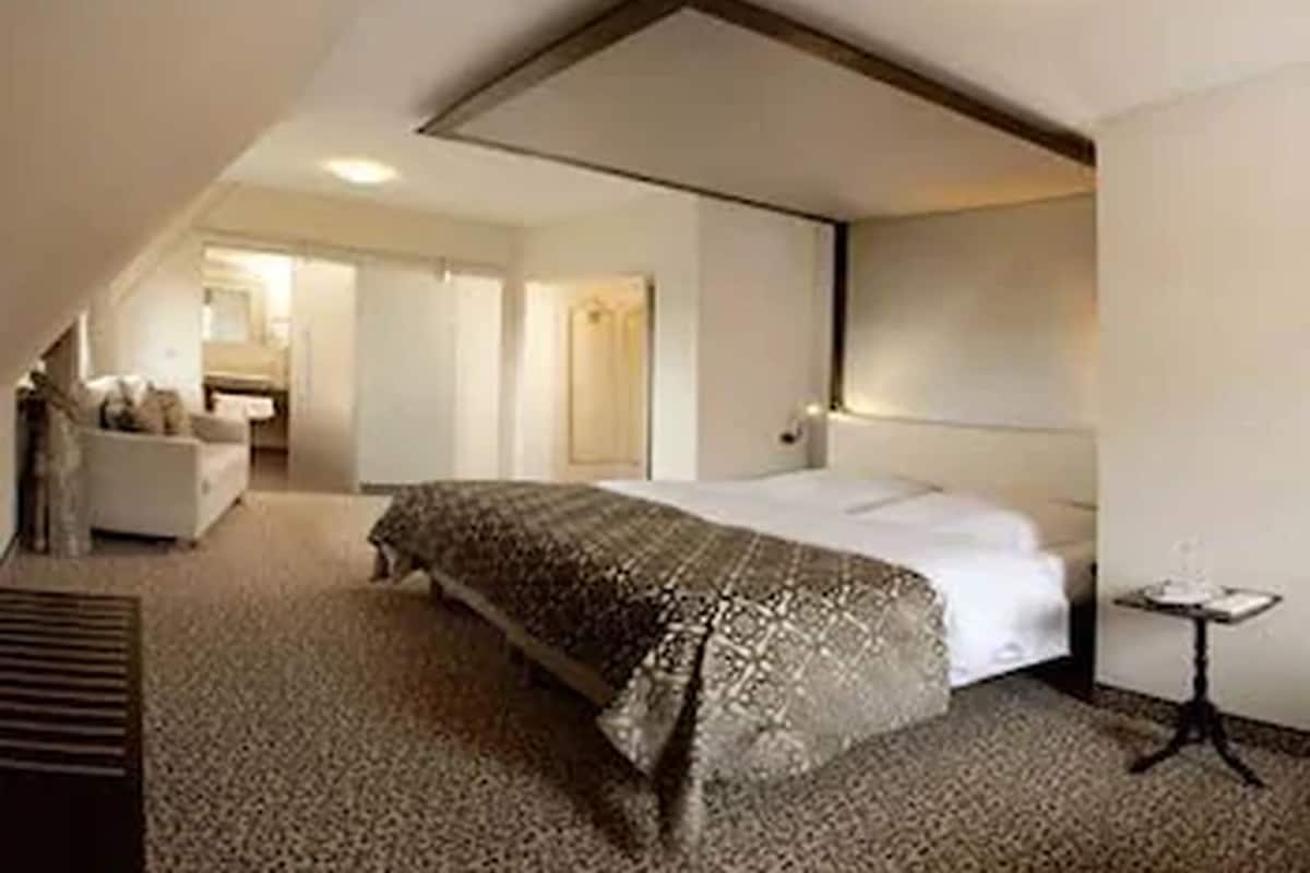 A hotel room with a large bed, a small table, and a sofa in the corner.