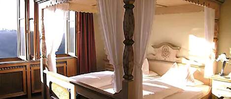 A four-poster bed with a canopy, a wooden nightstand, and a bedside table with a lamp.